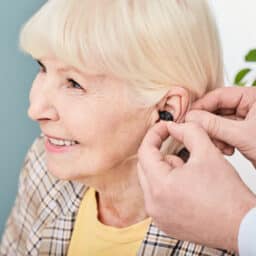 Smiling senior woman getting fitted for hearing aids.