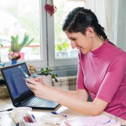 Woman with hearing loss looks at phone at work