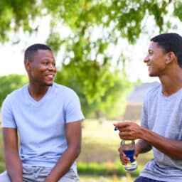Man with hearing aid talking to his friend in the park
