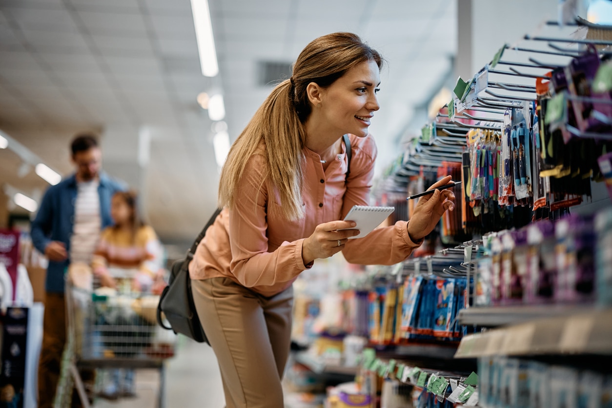 Woman using a shopping list and shopping for pens in the grocery store