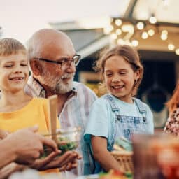Happy family enjoying an outdoor barbecue on a pleasant summer evening. Grandfather and his grandchildren having summer fun.