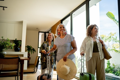 Travelling group of friends arrives at their vacation rental with their luggage.